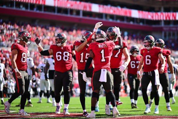 TAMPA, FLORIDA - DECEMBER 08: Rachaad White #1 and Luke Goedeke #67 of the Tampa Bay Buccaneers celebrate after a touchdown during the first quarter against the Las Vegas Raiders at Raymond James Stadium on December 08, 2024 in Tampa, Florida. (Photo by Julio Aguilar/Getty Images)